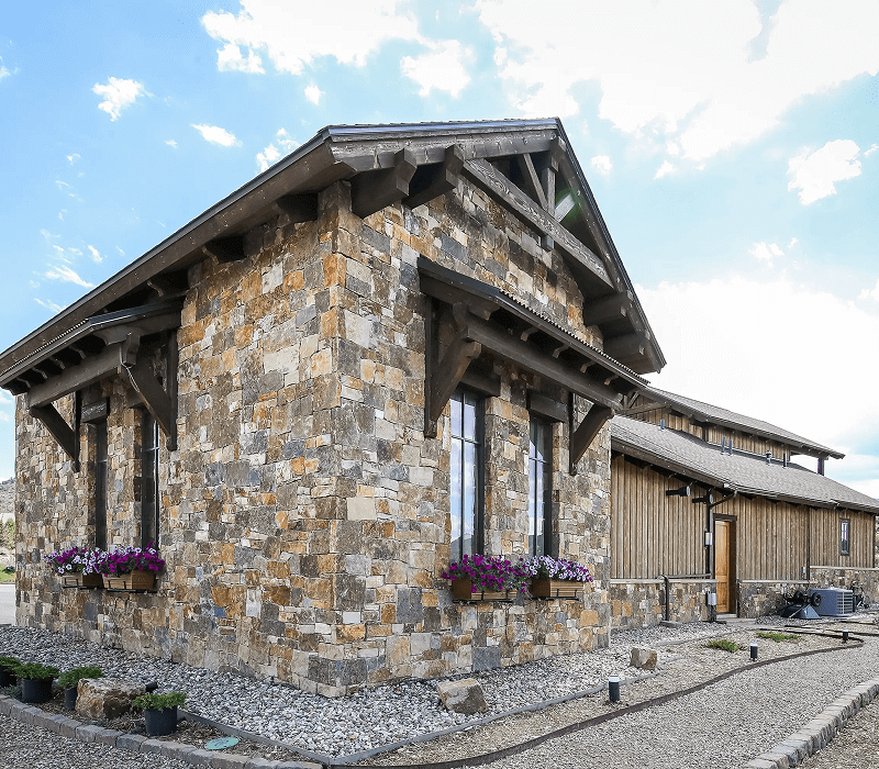 Stone house with flower boxes under windows and a clear sky.