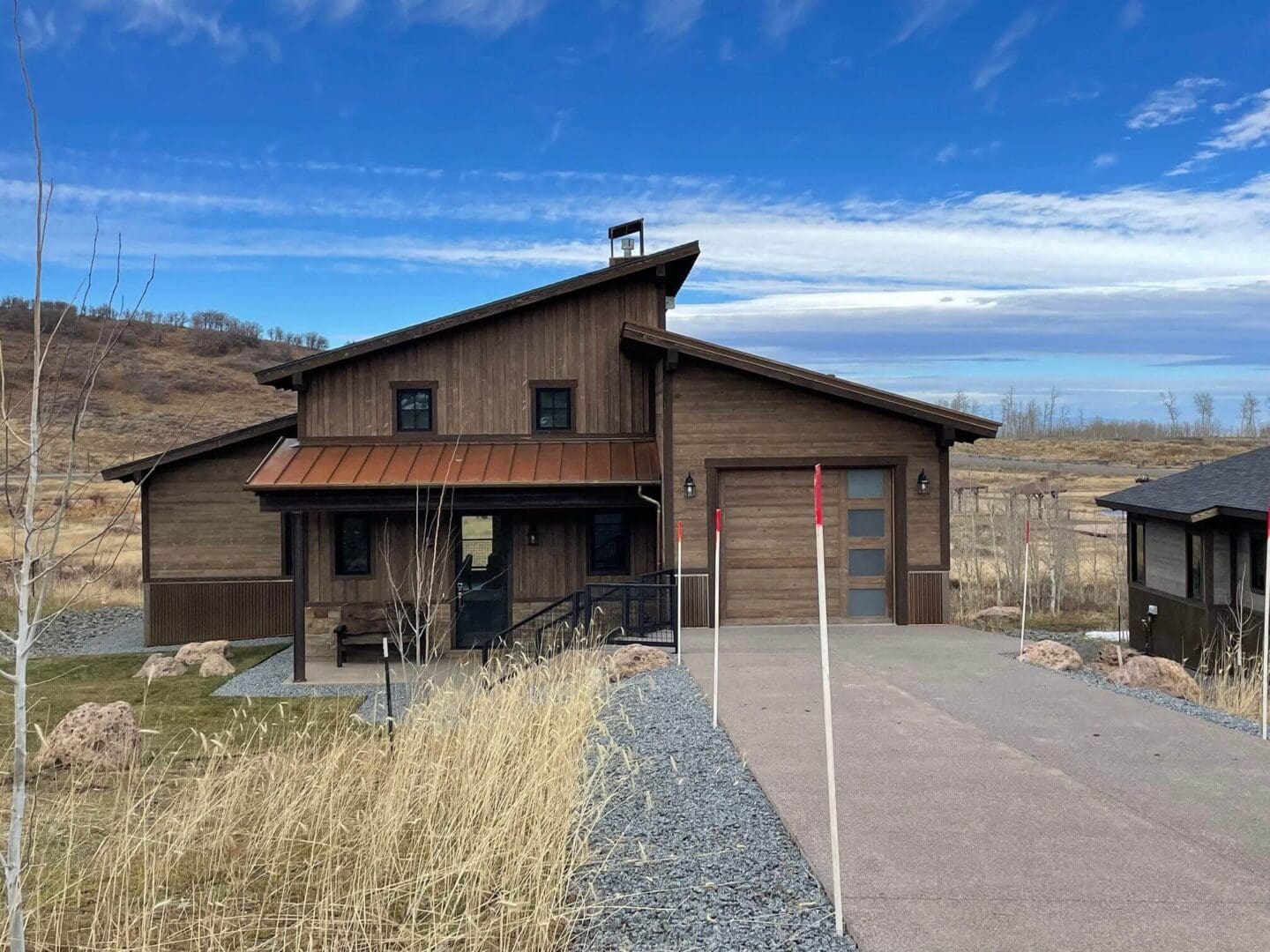 Modern rustic house with a wooden exterior and attached garage under a blue sky.