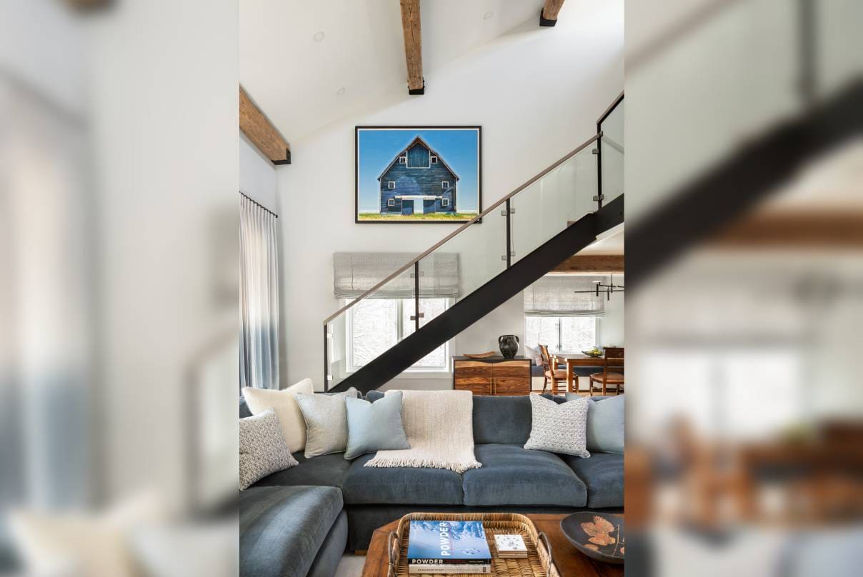 Modern living room with a floating staircase and large artwork.