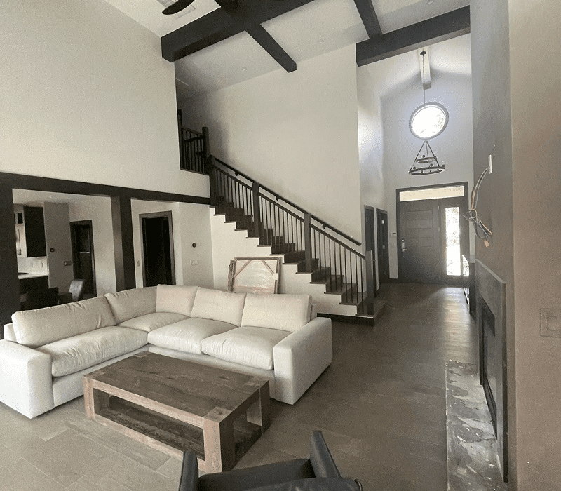 Spacious modern living room with white sectional sofa and wooden beams.