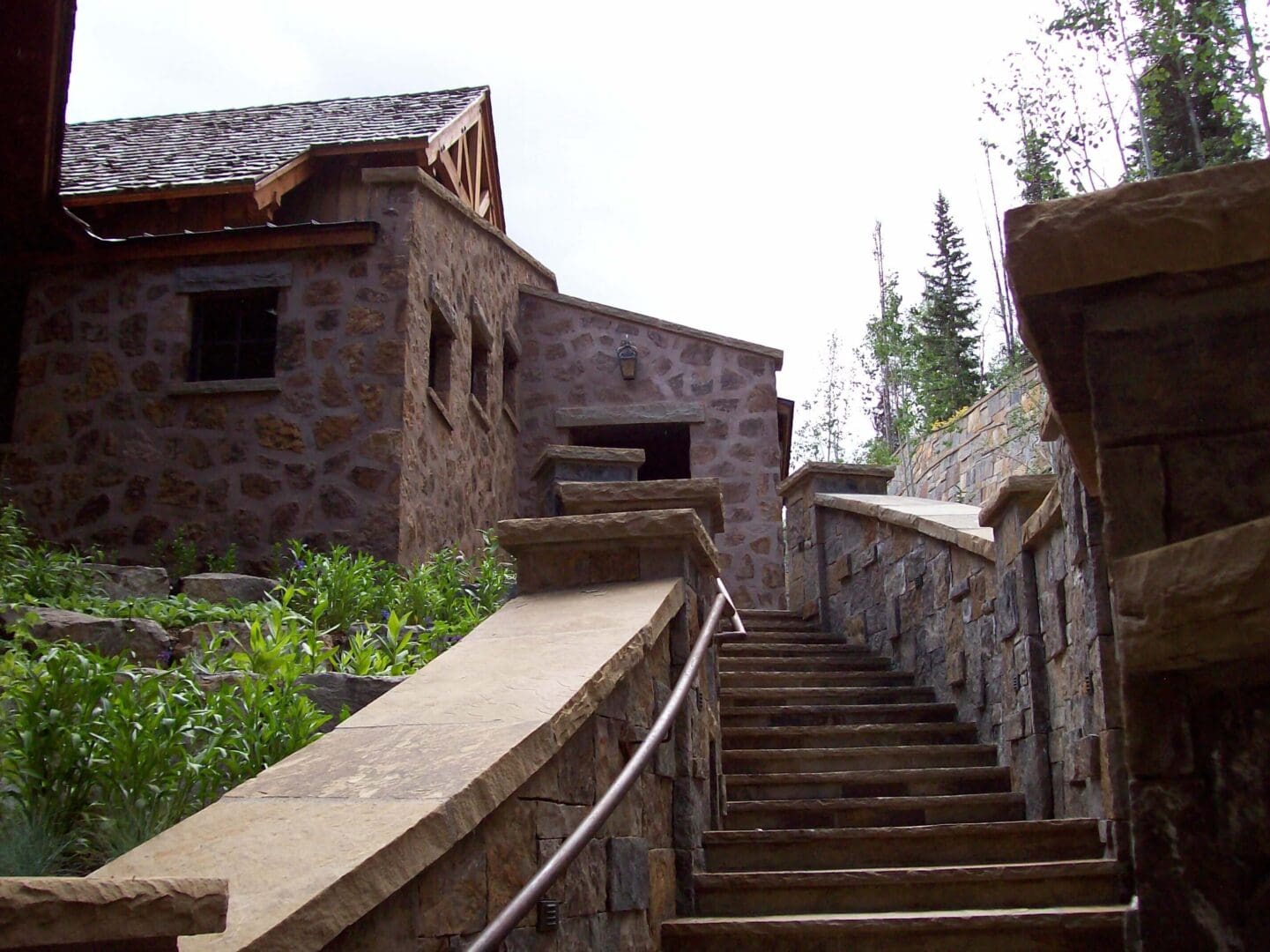Stone building with stairs and greenery under a bright sky.