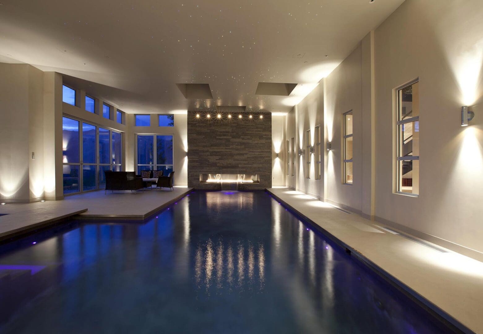 Modern indoor pool with elegant lighting and large windows.